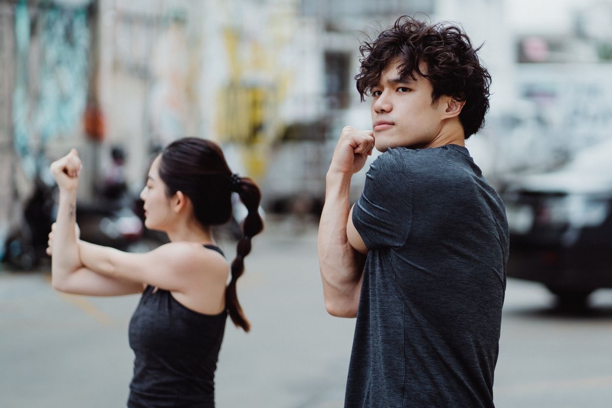 two young people stretching their arms across their chests before a run