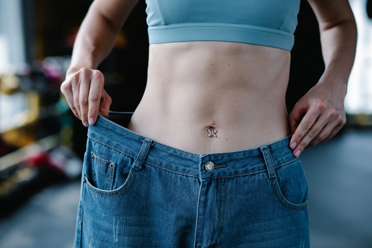 slim woman wearing pants that are too large to highlight her weight loss success