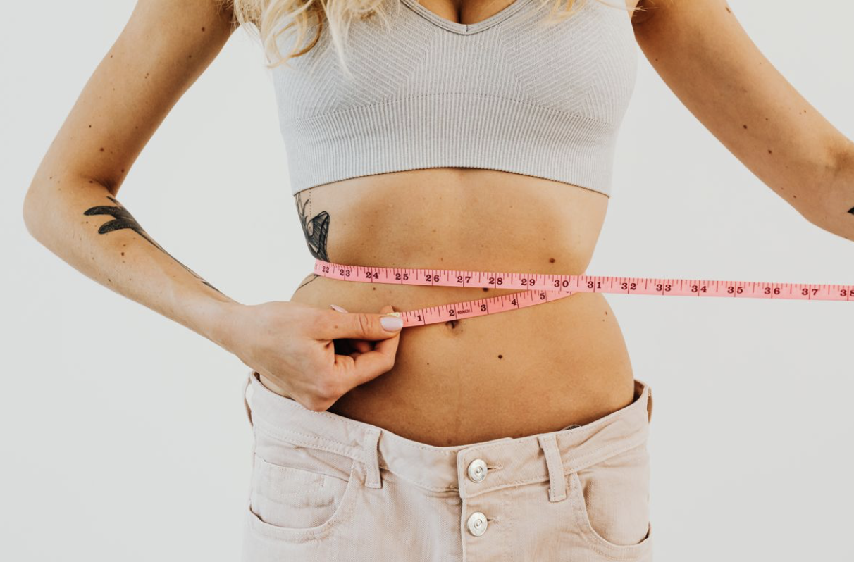 woman taking berberine for weight loss measuring her waist with a fabric measuring tape
