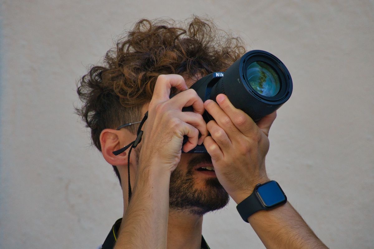 man looking through a camera to take a photo of a tree
