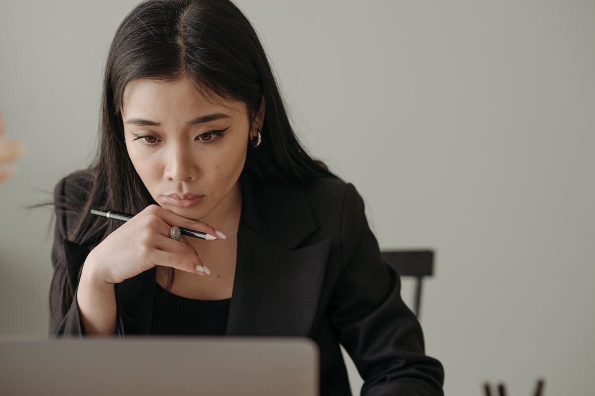 woman in a blazer  leaning forward to focus on her laptop