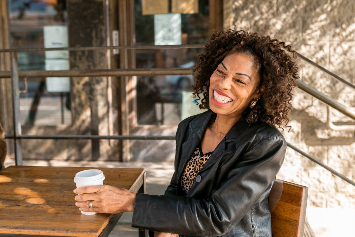 smiling woman laughing and having a cup of coffee