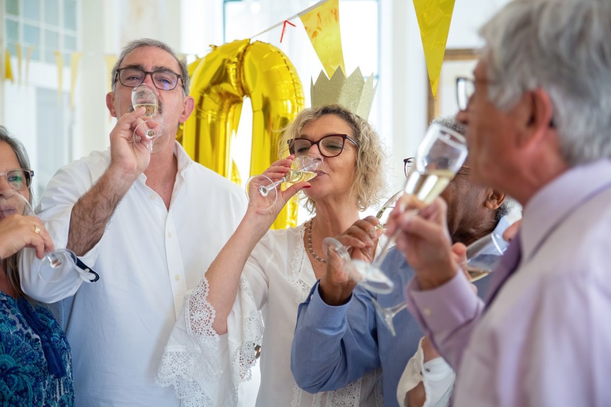 older adults celebrating a birthday by drinking flutes of champage