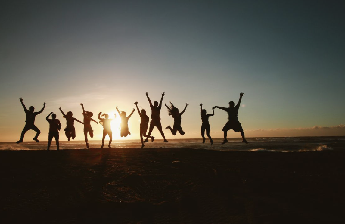 silhouettes of several people lined up against the sunrise