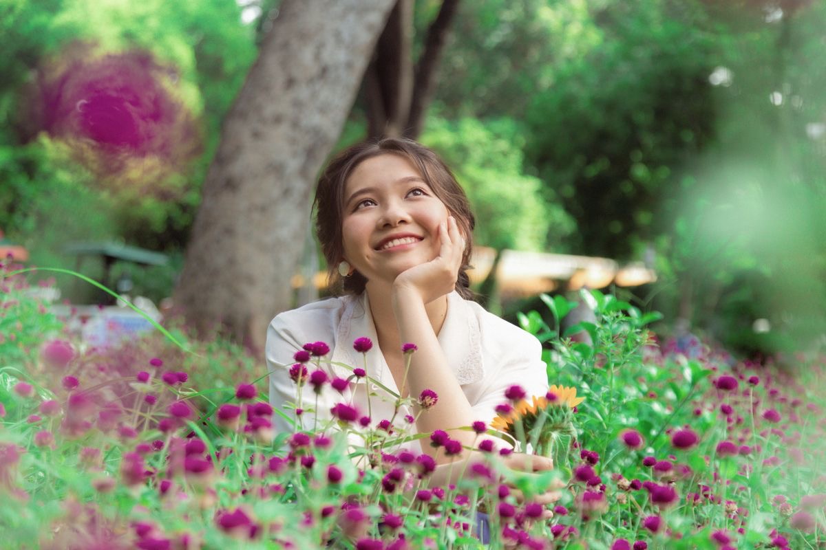 woman seated in a field of purple flowers smiling happily