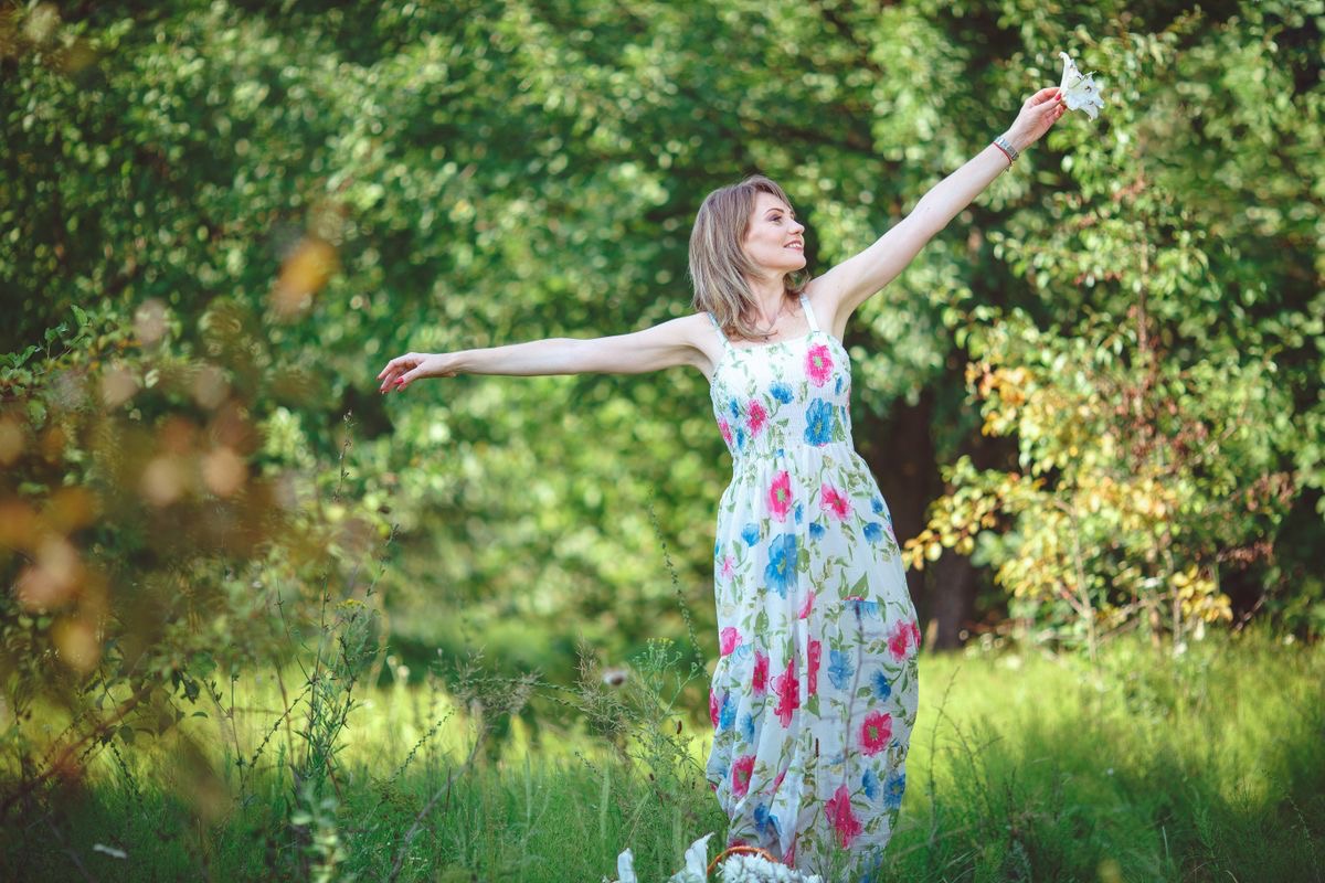 woman with her arms stretched out enjoying a grassy field