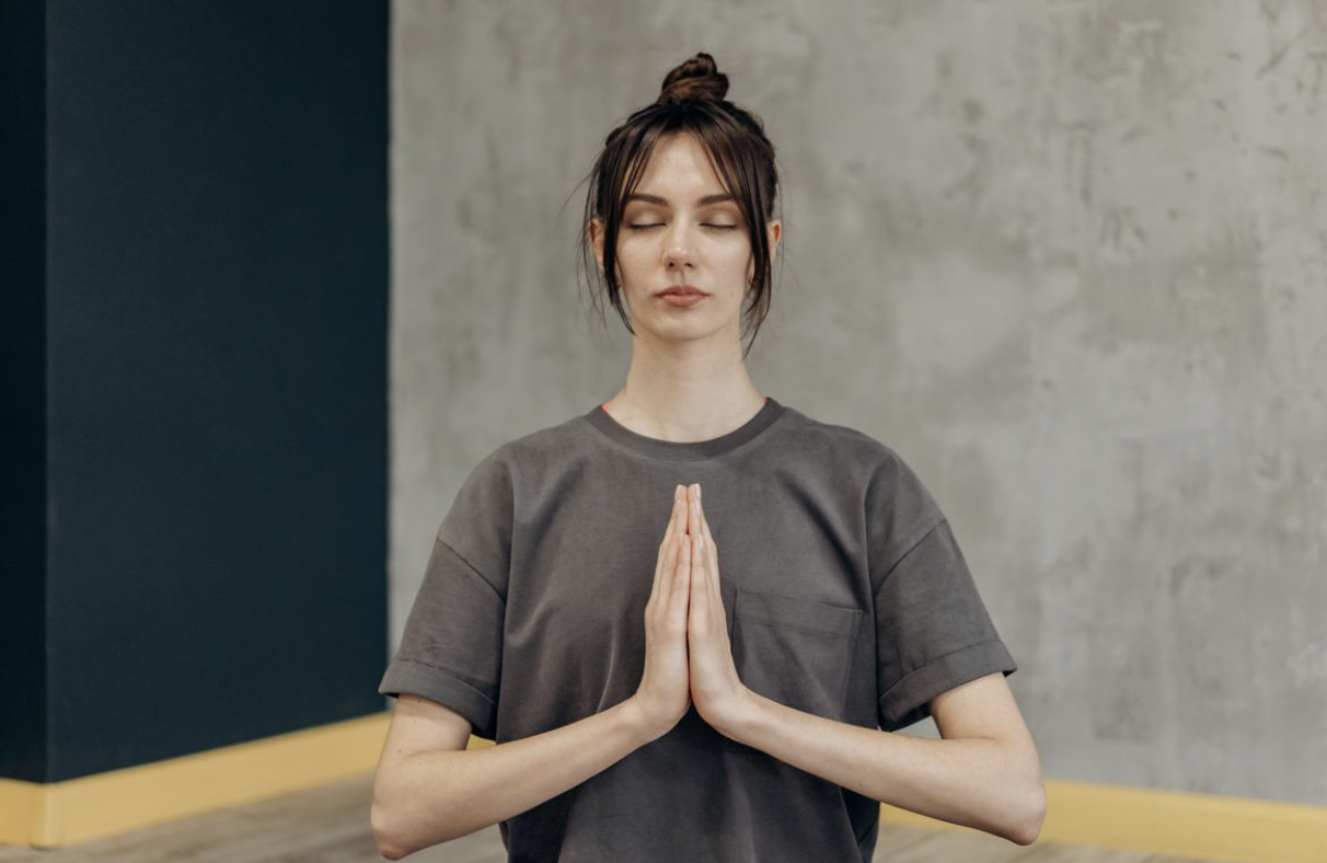 woman with her hands pressed together and eyes closed, meditating