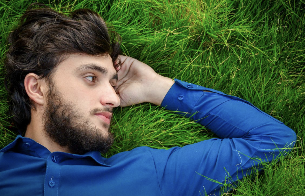 man with thick hair lying in the grass