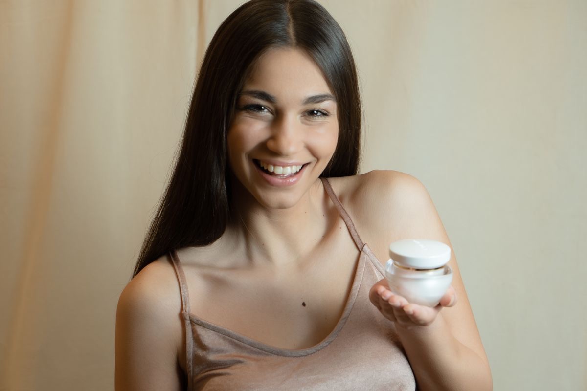 woman holding a jar of face cream