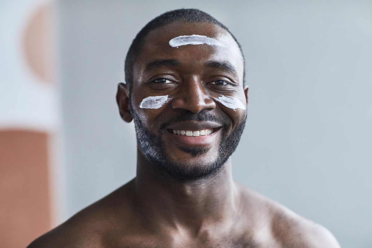 man with face creams dabbed on his cheeks and forehead