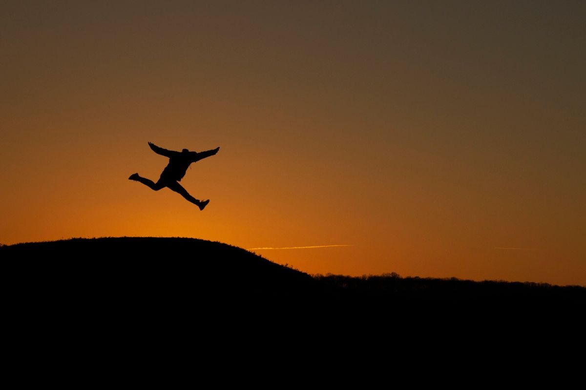 figure running down a hill backlit by the sunset