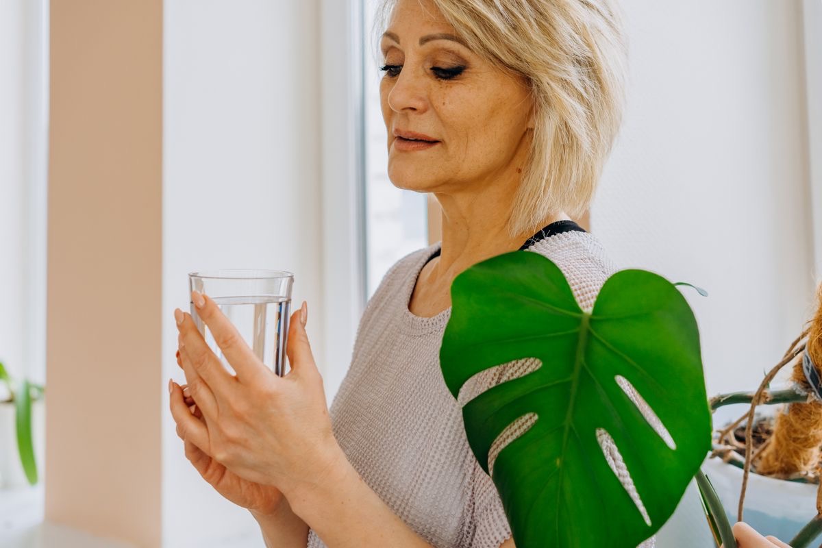 woman holding a glass of water as she takes her wellness supplements