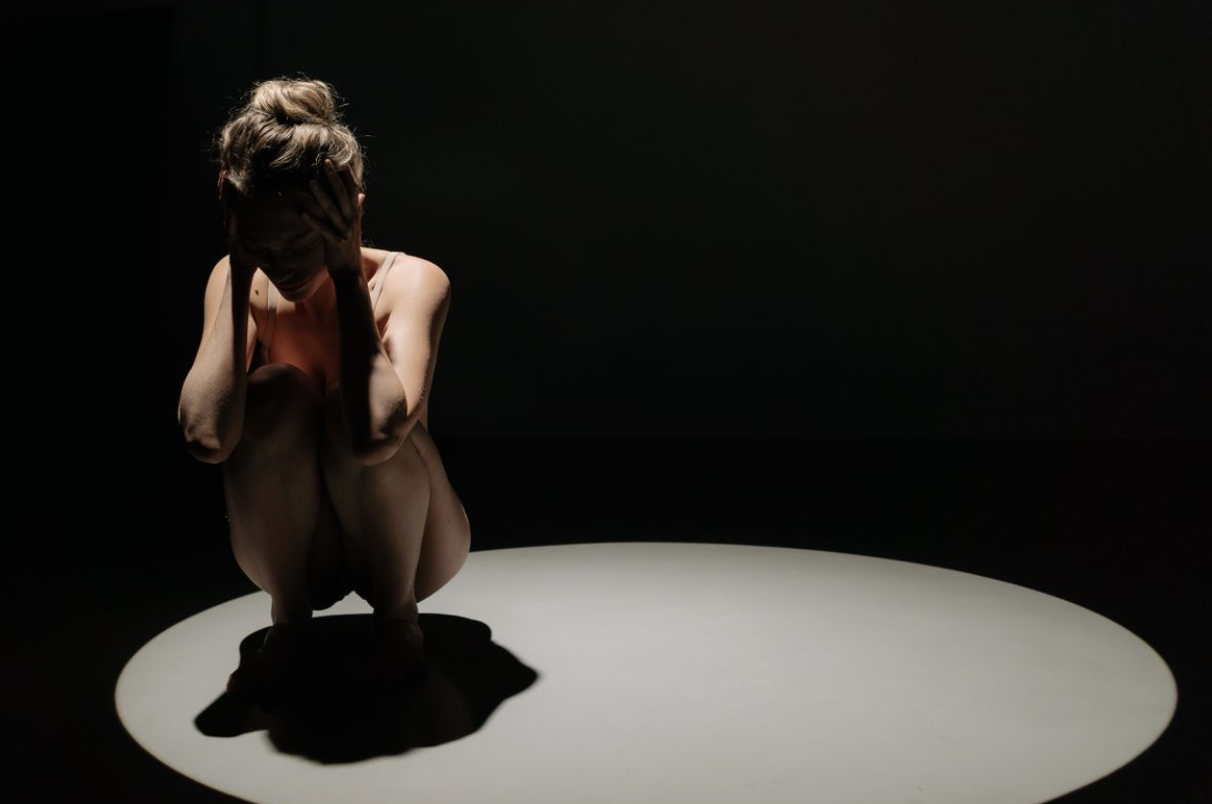 stressed woman having a panic attack in the spotlight, demonstrating how anxiety and cortisol can control someone's life