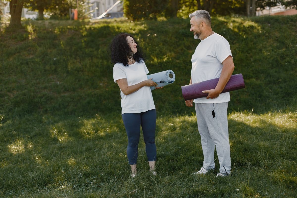 older couple doing yoga in the park