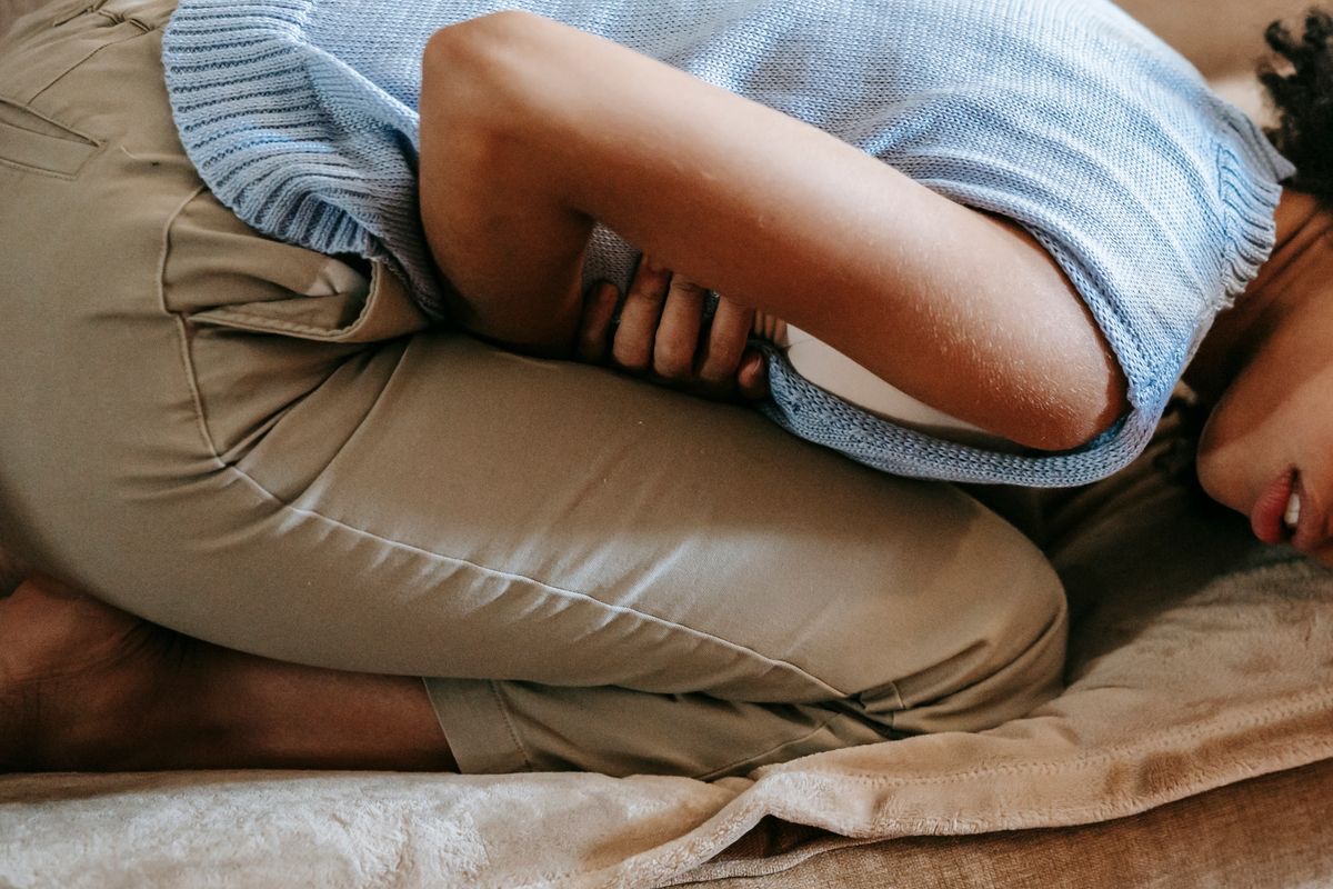 woman doubled over due to stomach discomfort