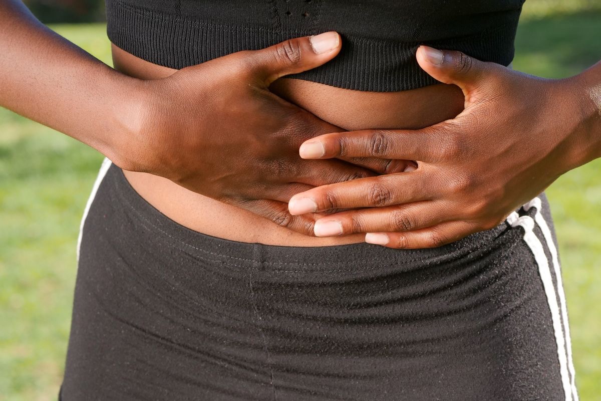 woman holding her stomach in pain caused by leaky gut syndrome symptoms