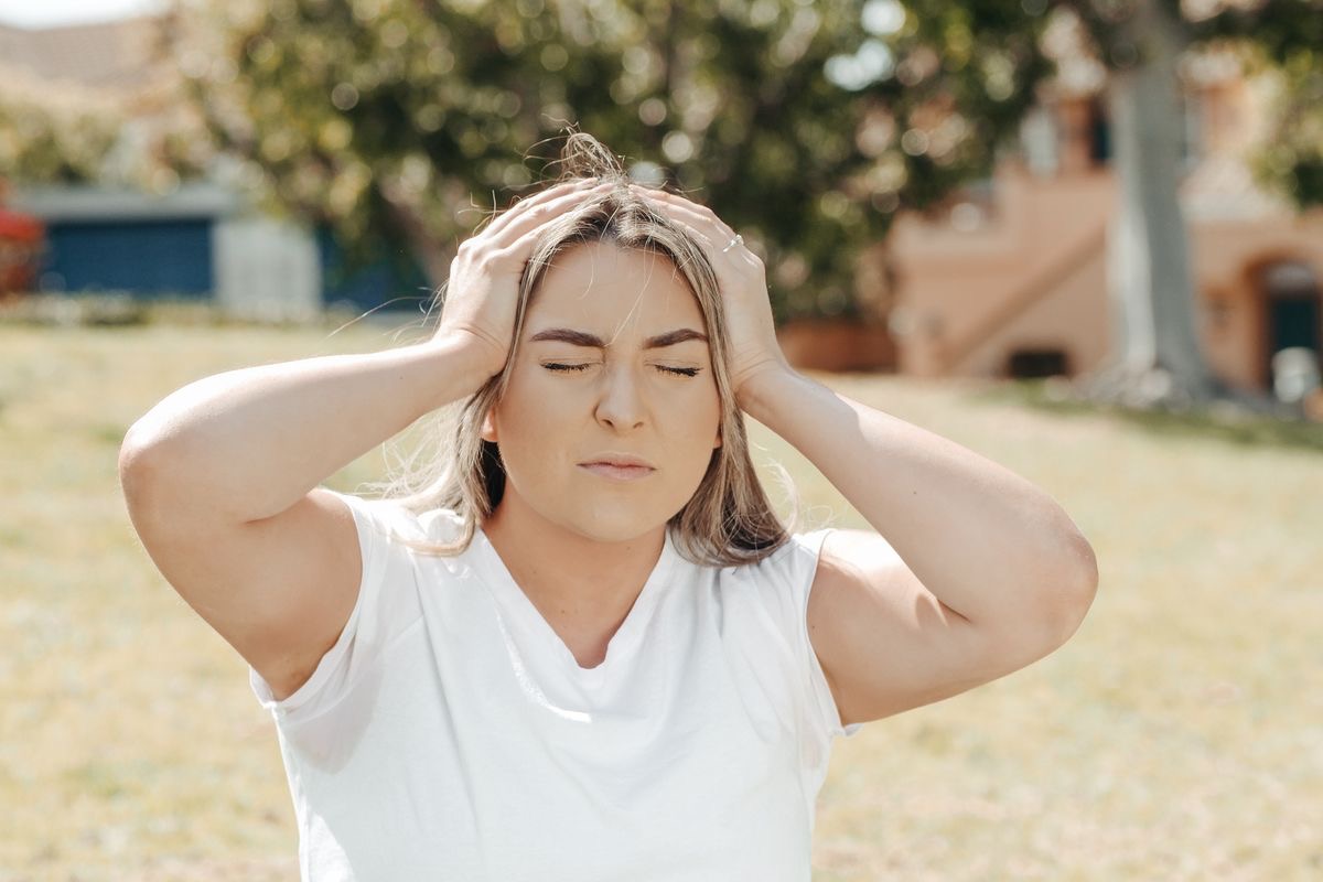 woman holding her head with both hands, suggesting she is suffering from brain fog
