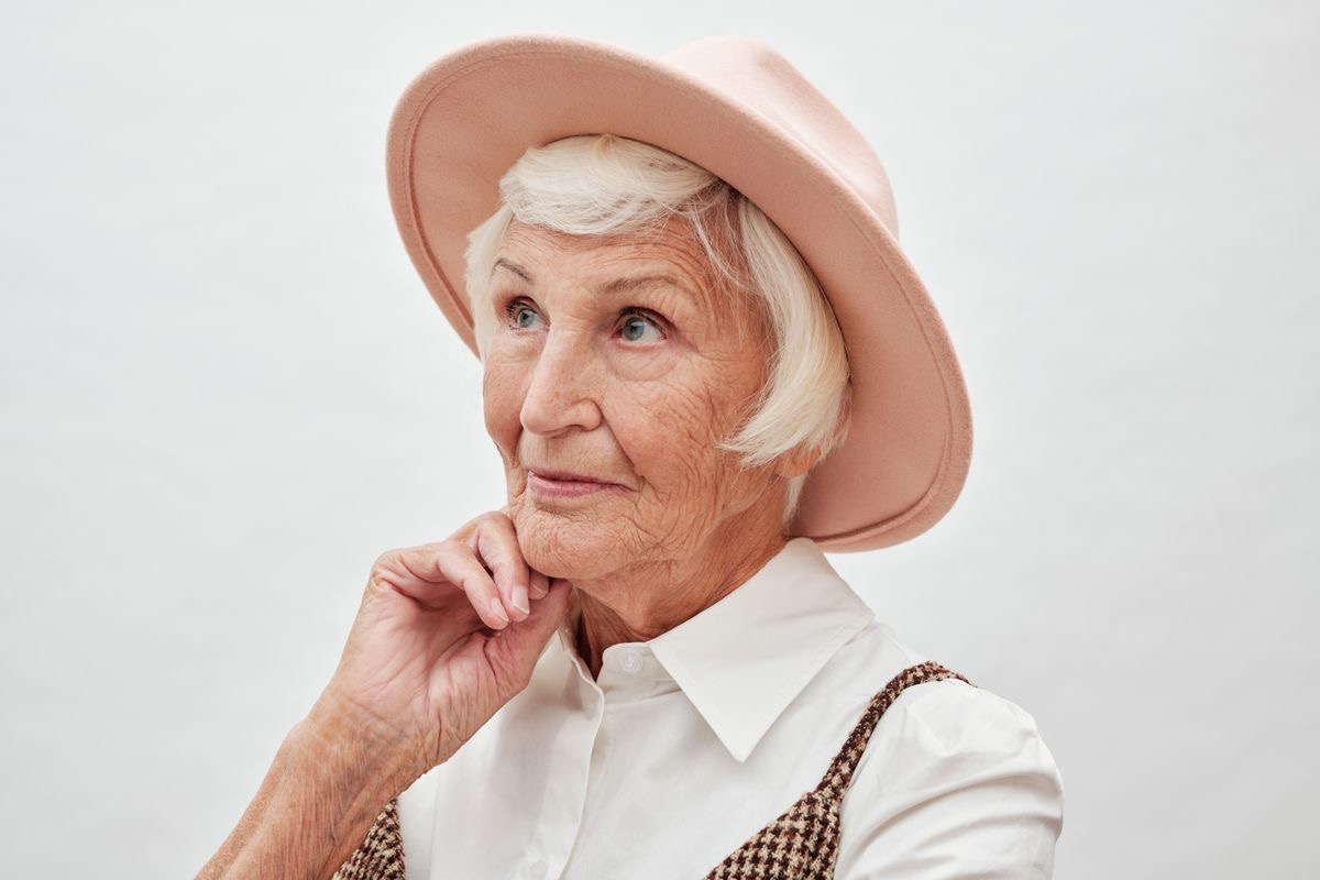older woman posing in a stylish pink hat