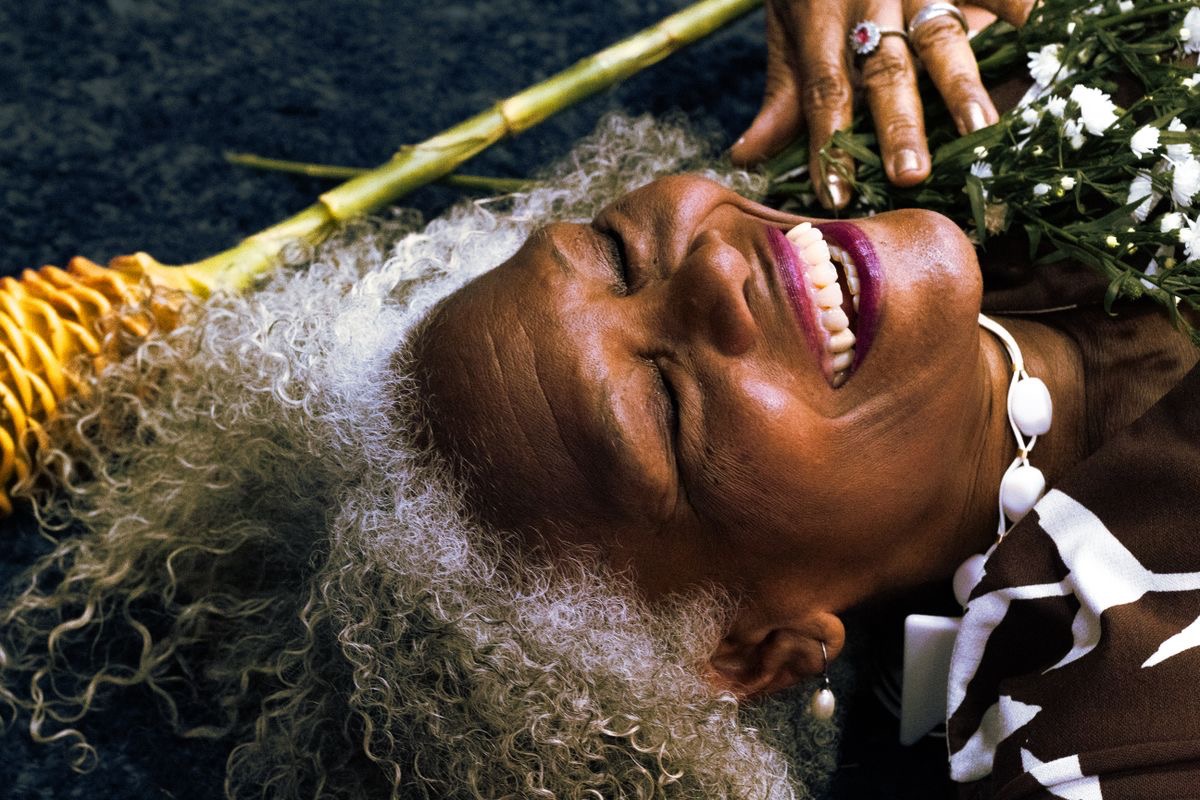 older woman who has preserved her vitality lying back in the flowers laughing