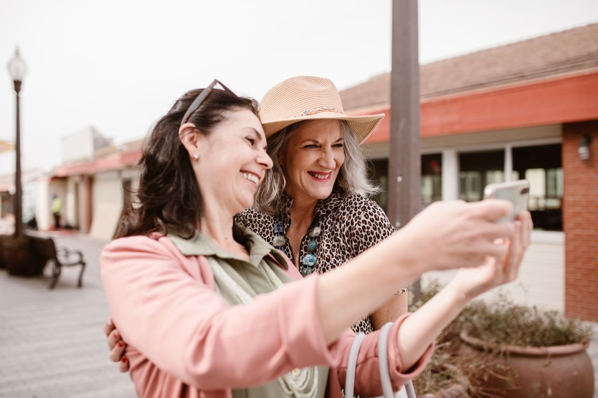 women laughing and taking a selfie at a farmer's market