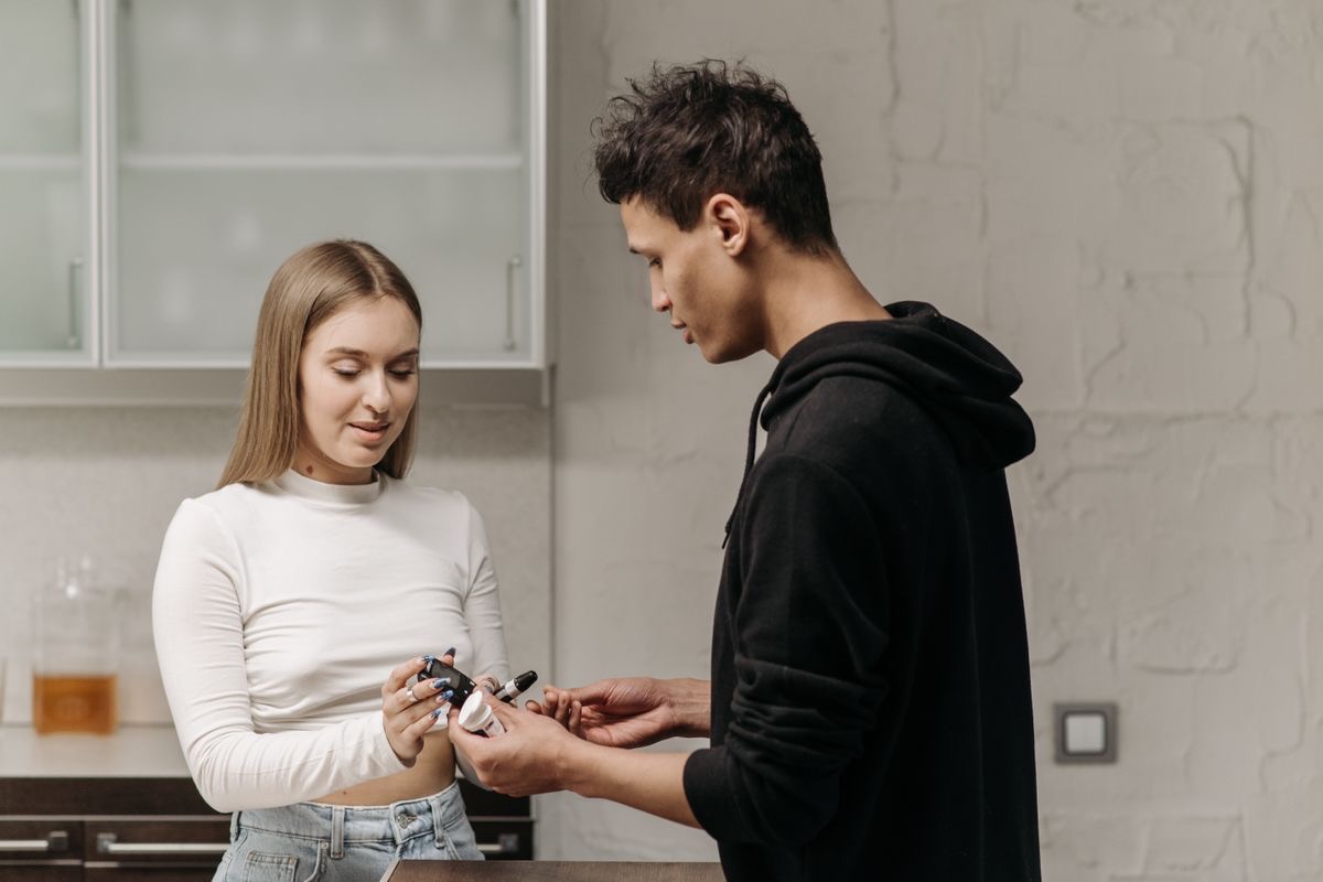 woman helping her partner check blood sugar levels at home