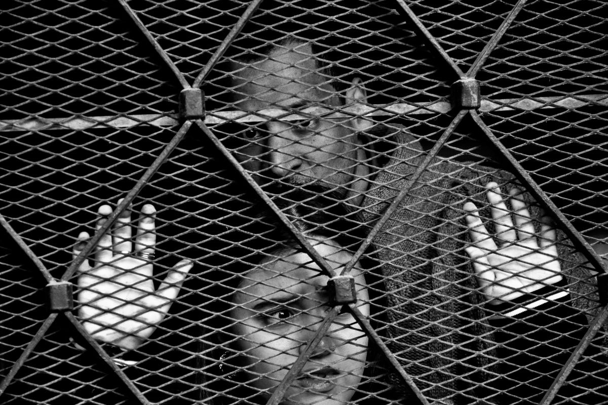two people behind a metal grate indicating feeling trapped by poor mental health