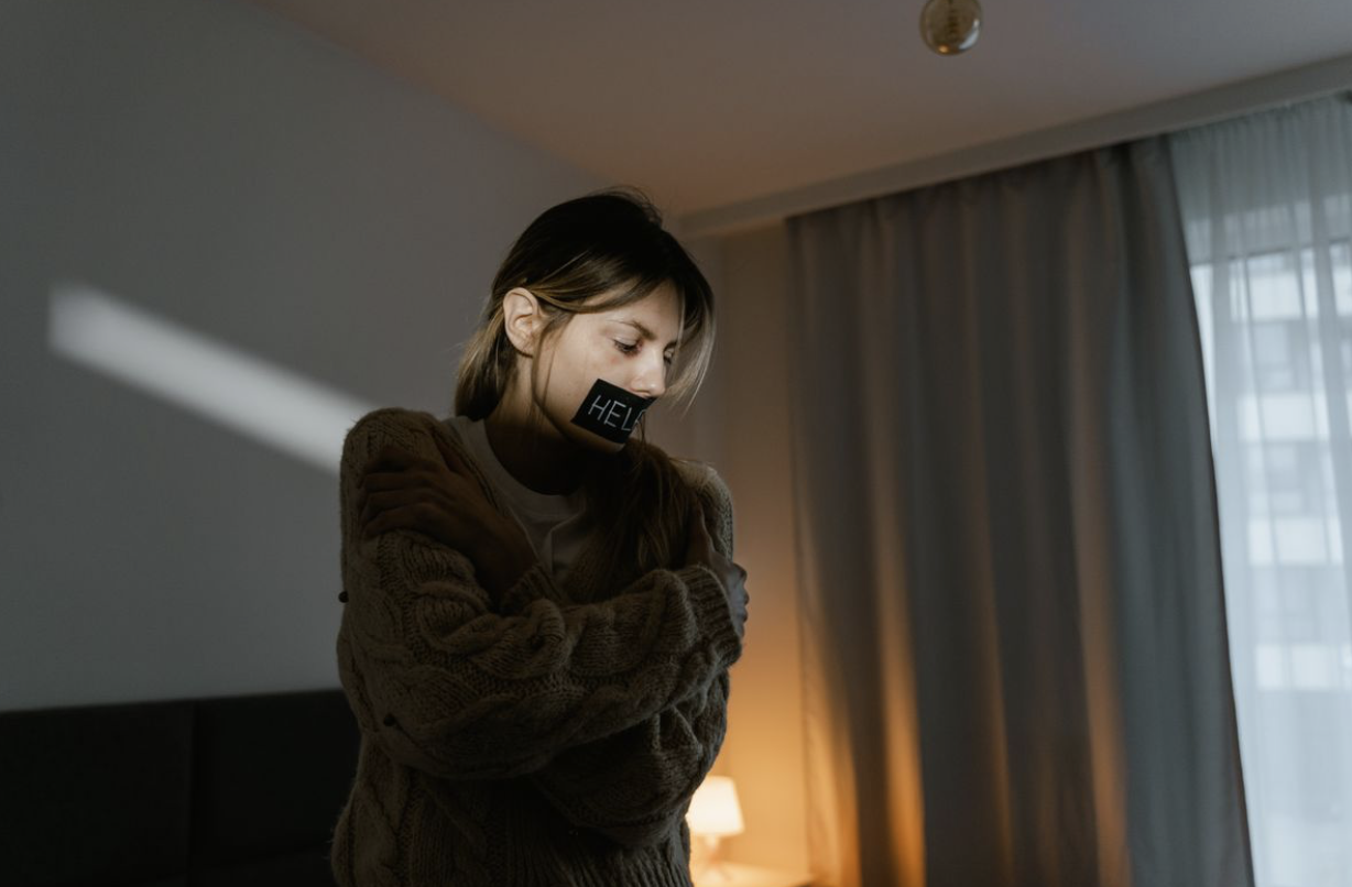 woman with tape over her mouth that reads help, representing the quiet suffering of people with mental health struggles