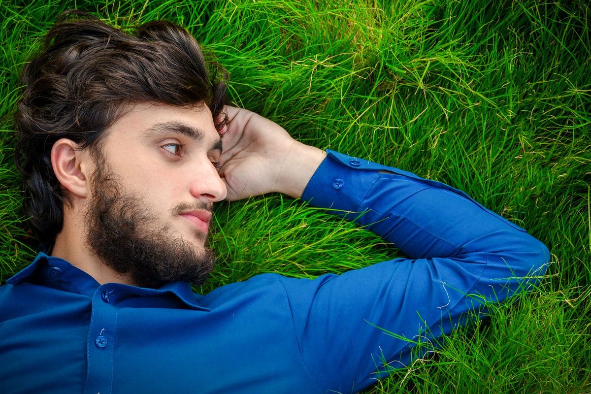 man with luscious brown hair lying in the grass