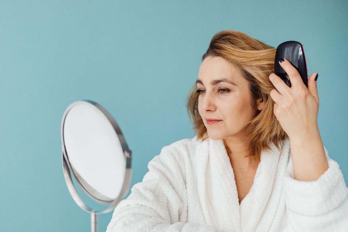 woman brushing her hair, thinking about how it's gotten thinner since experiencing weight loss