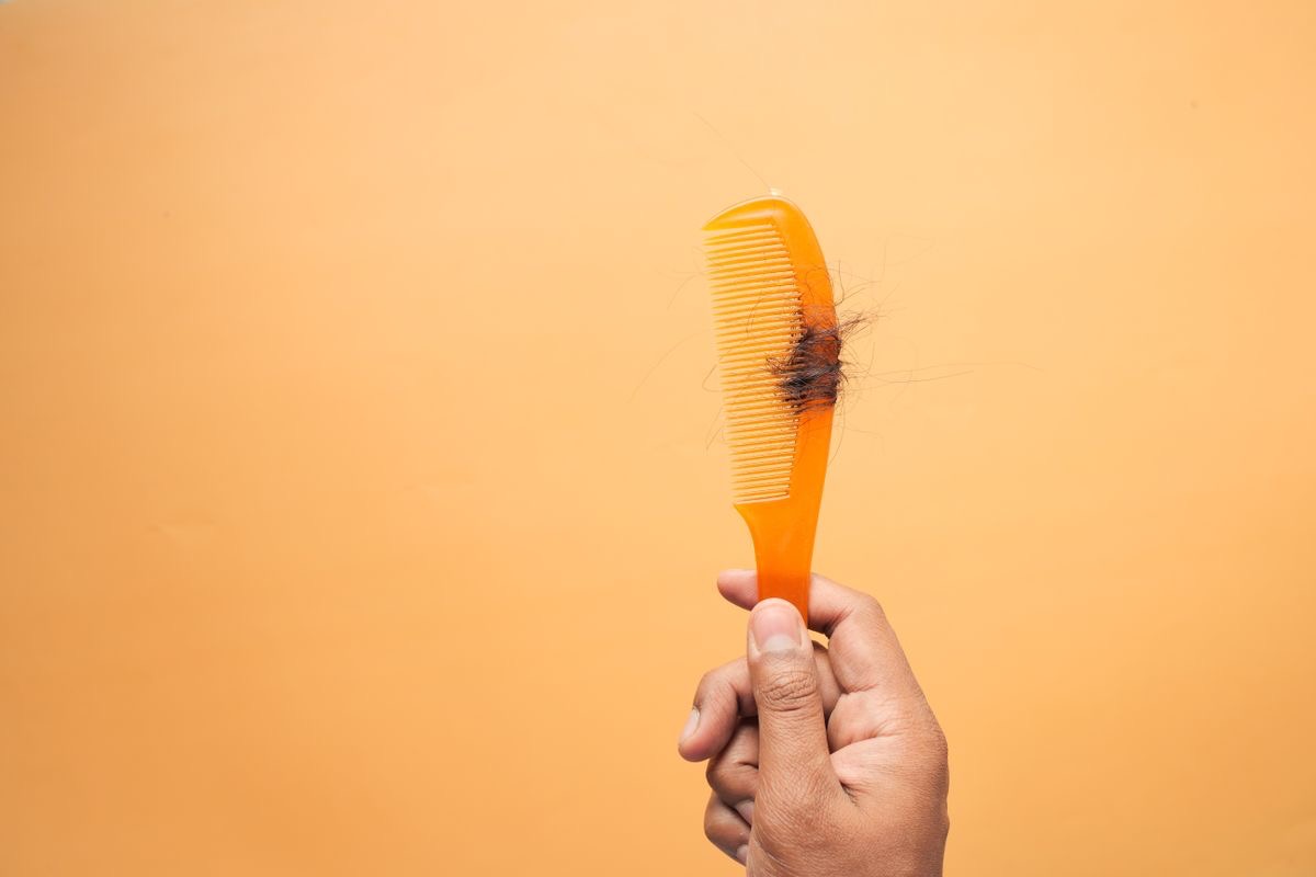 comb with hair tangled around the bristles indicating that hair is falling out