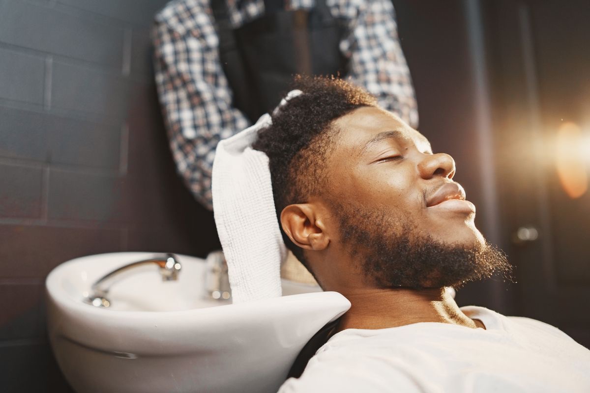 man with thick healthy hair getting shampooed at a barbershop
