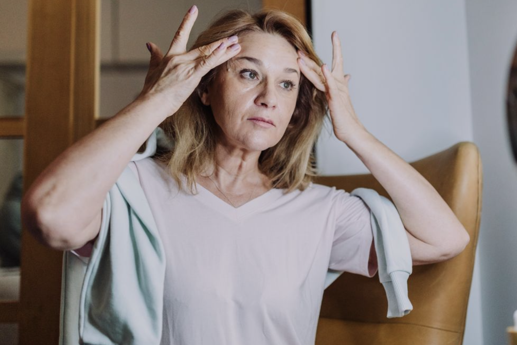 woman examining her skin for signs of aging