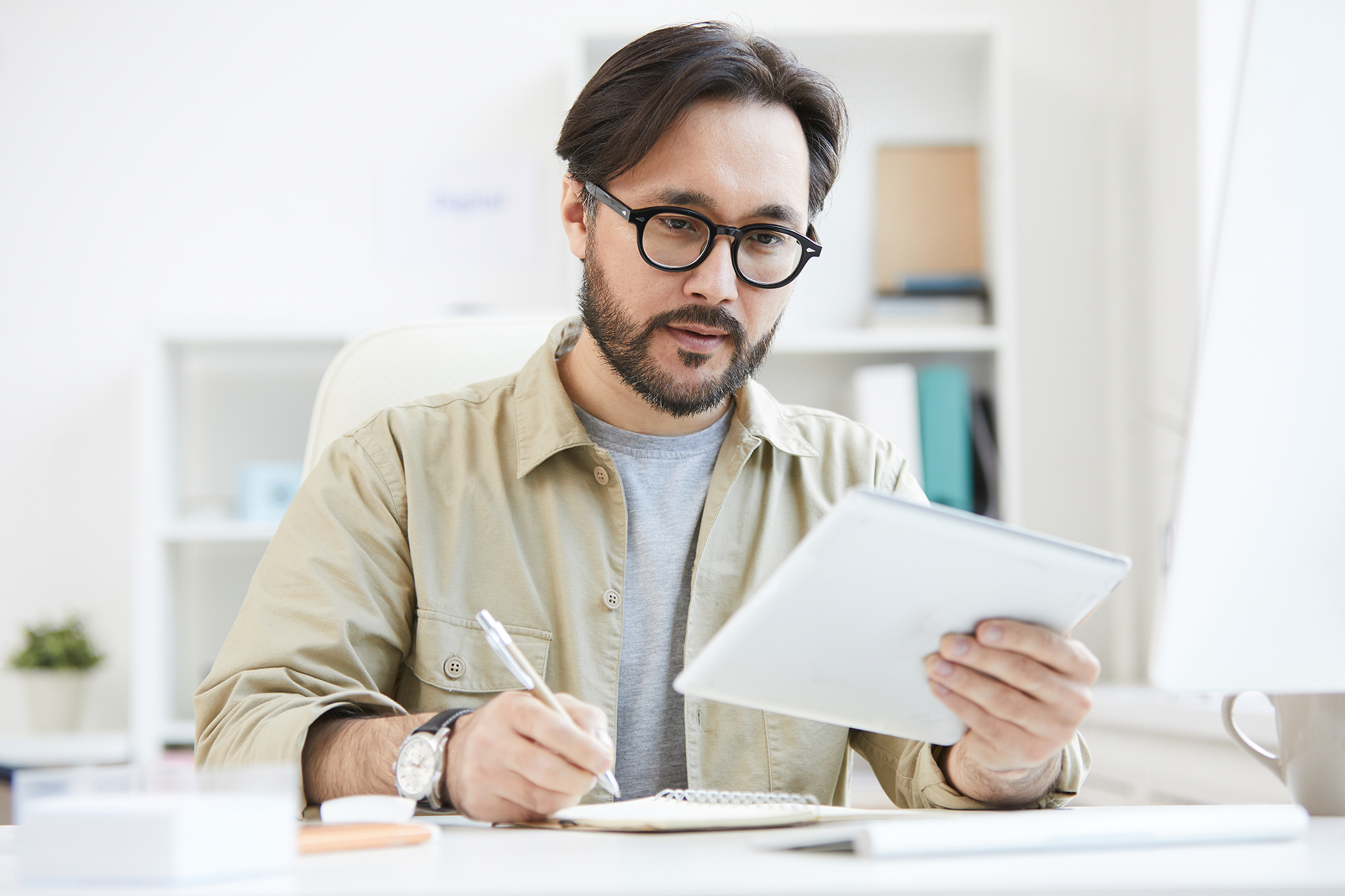 Consultant reviewing analytics on a tablet and taking notes, representing data-driven decision-making in global mental health benefits.