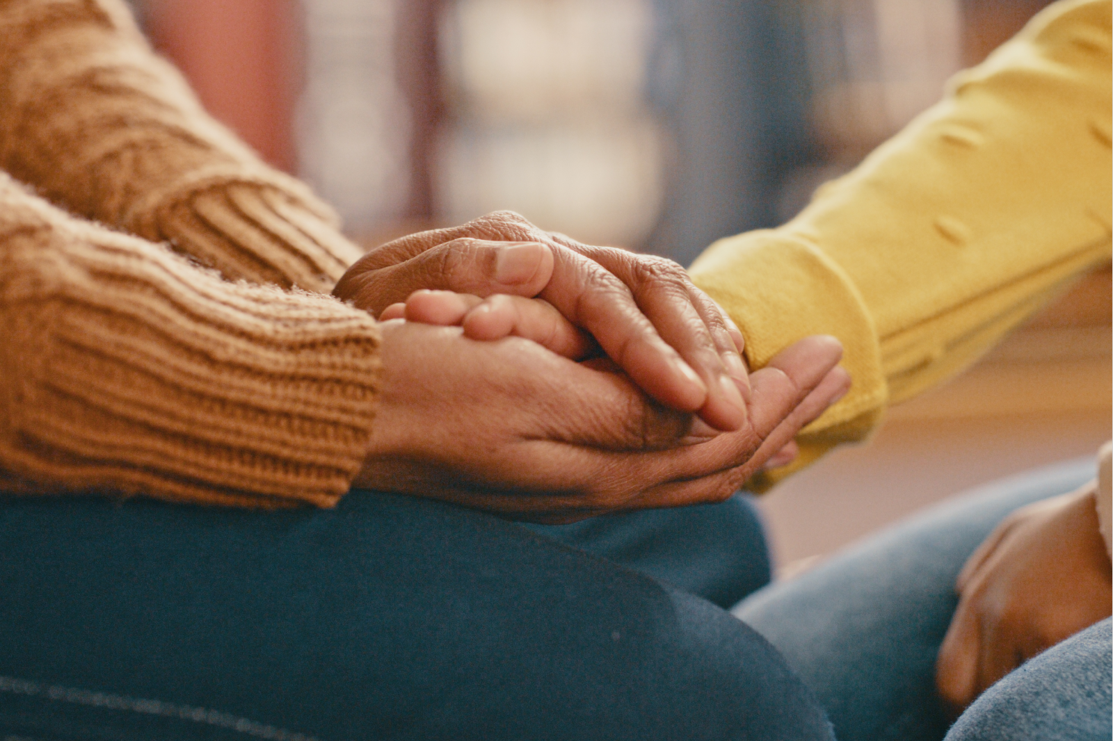 Close-up of two people holding hands in support, symbolizing compassion and connection during difficult times.