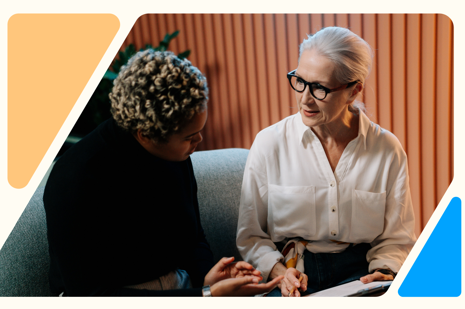 Two colleagues sitting together and having a thoughtful conversation, symbolizing workplace support and empathy for employees managing cancer and its impact on mental health.