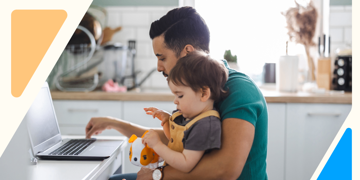A man works from home with his toddler on his lap, symbolizing the connection between financial stress, family responsibilities, and workplace well-being.
