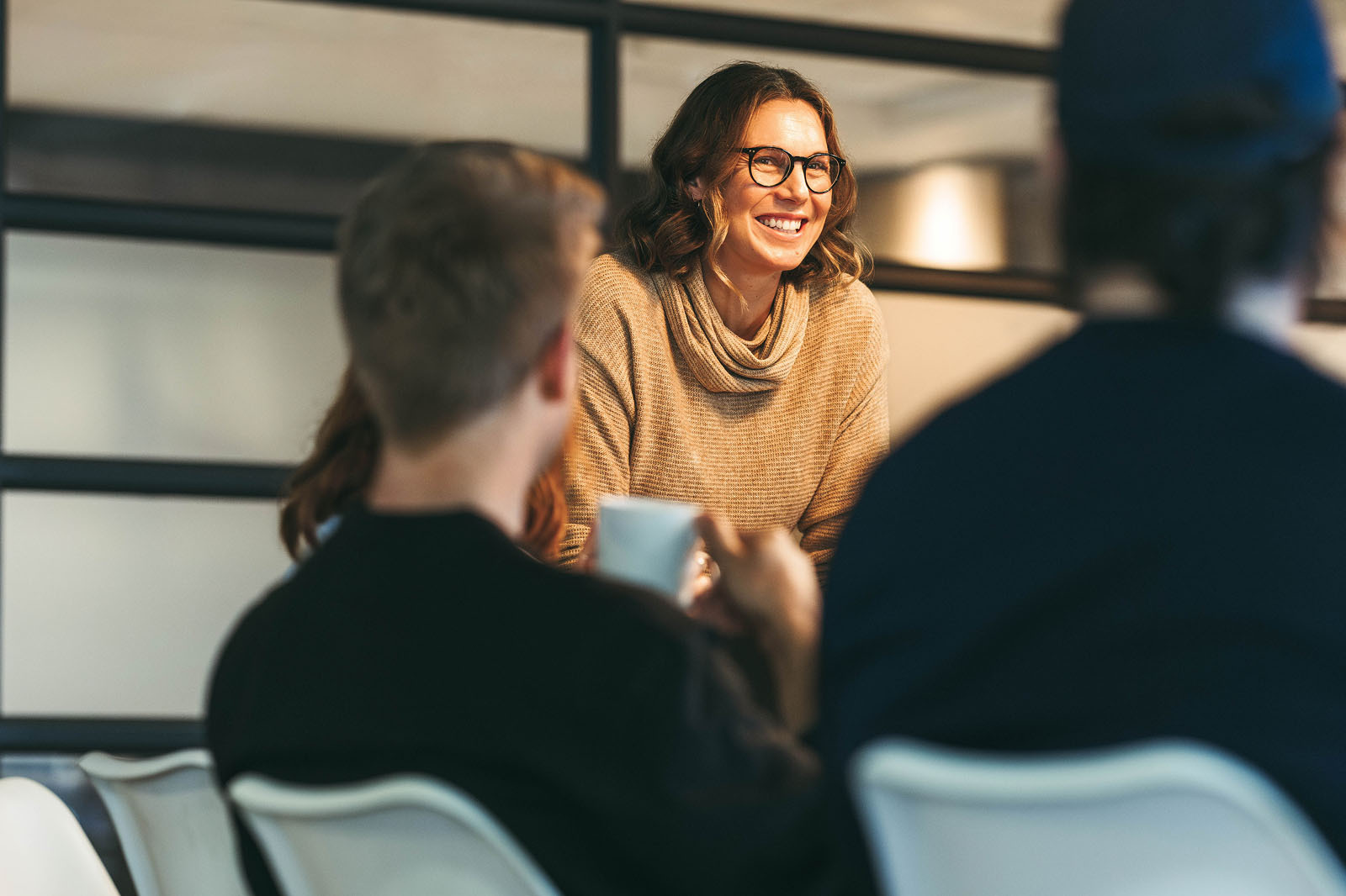 Woman leans into conversation around a table in a workplace setting