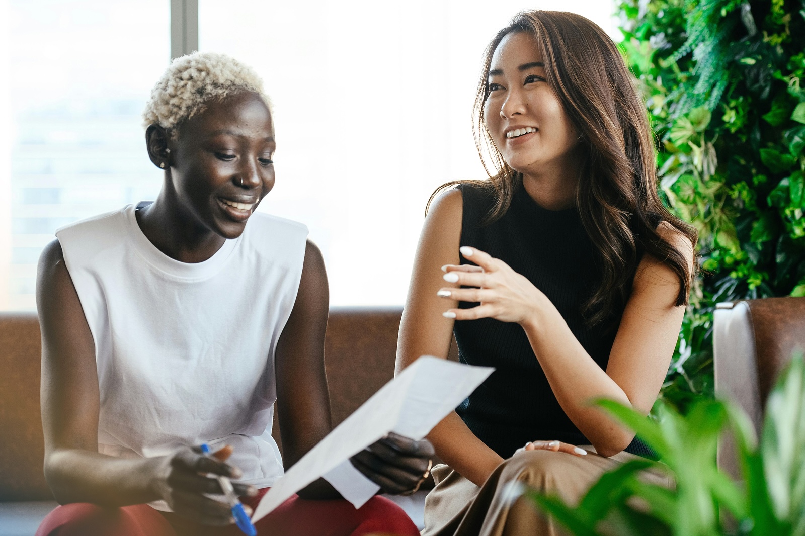 Two colleagues reviewing a document together in a collaborative setting, representing workplace support and connection in building resilience.