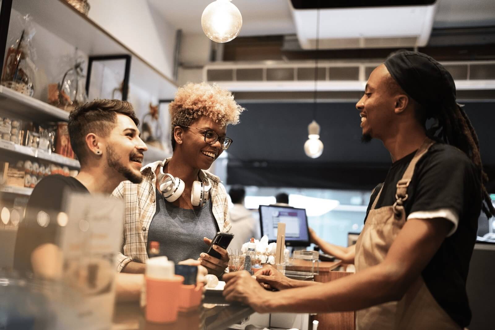 Retail employees interacting with customers at a store counter, representing frontline work and the emotional demands of customer-facing roles.