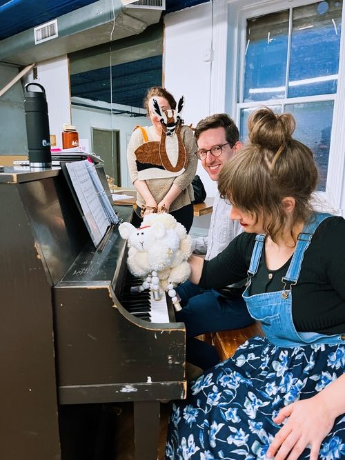 Artists rehearsing with puppets at a piano