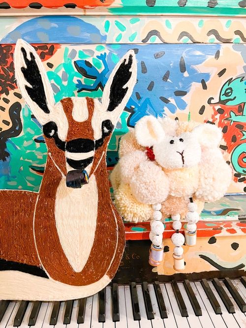 A gazelle puppet and a lamb puppet in front of a piano