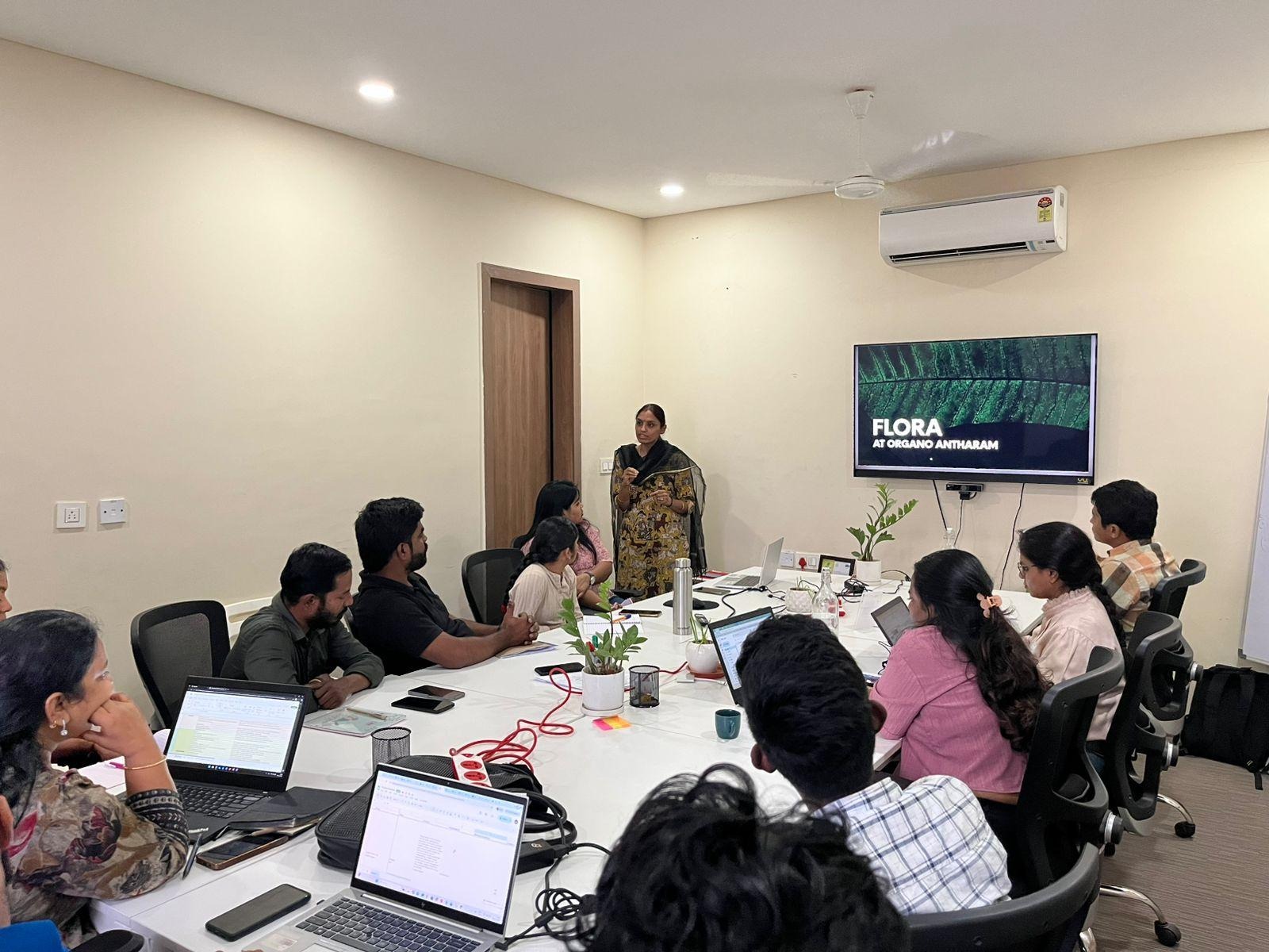 A person standing in front of a group of people sitting around a tableAI-generated content may be incorrect.