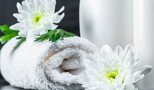 Rolled up white towel with some flowers around it