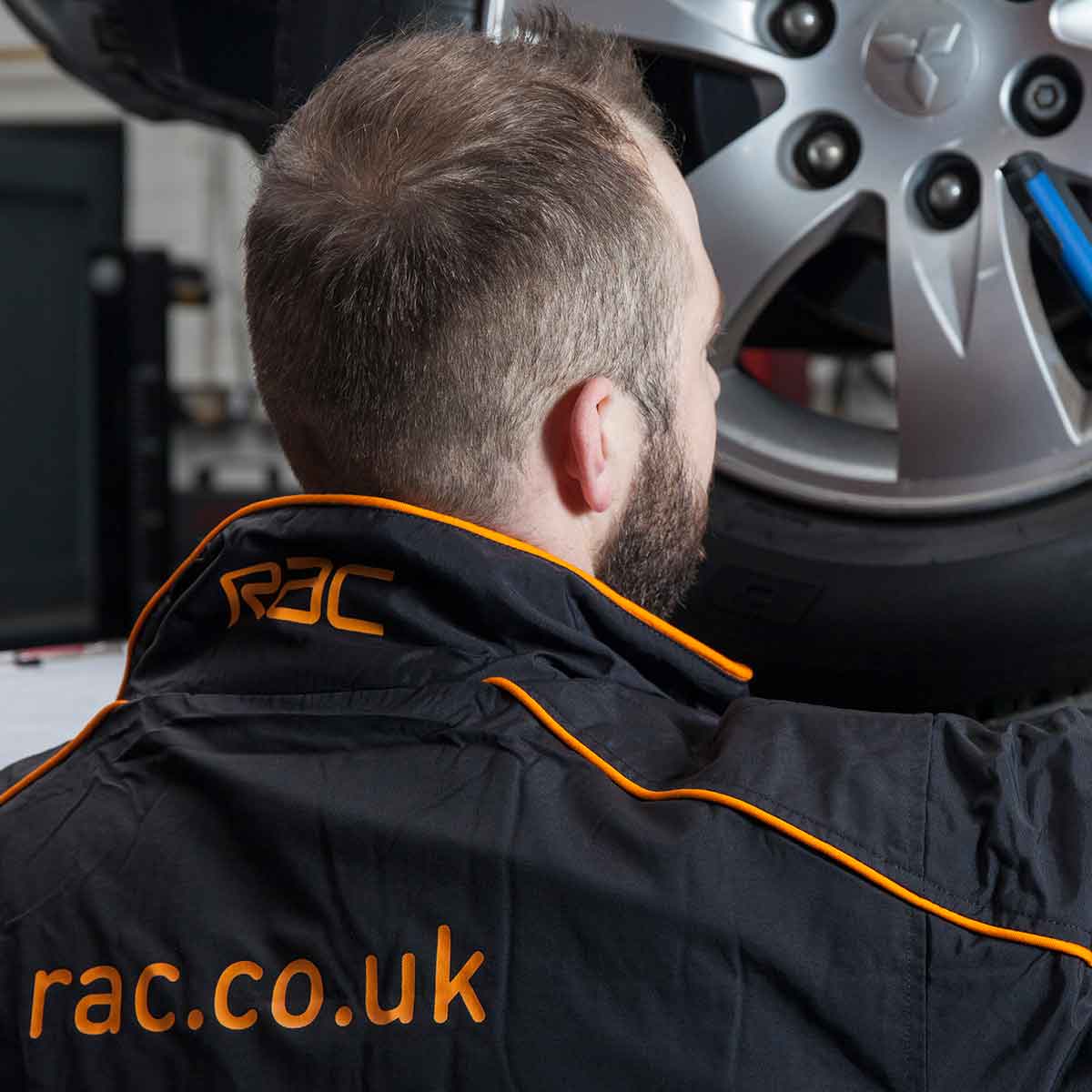 A technician wearing RAC overalls attending to a car