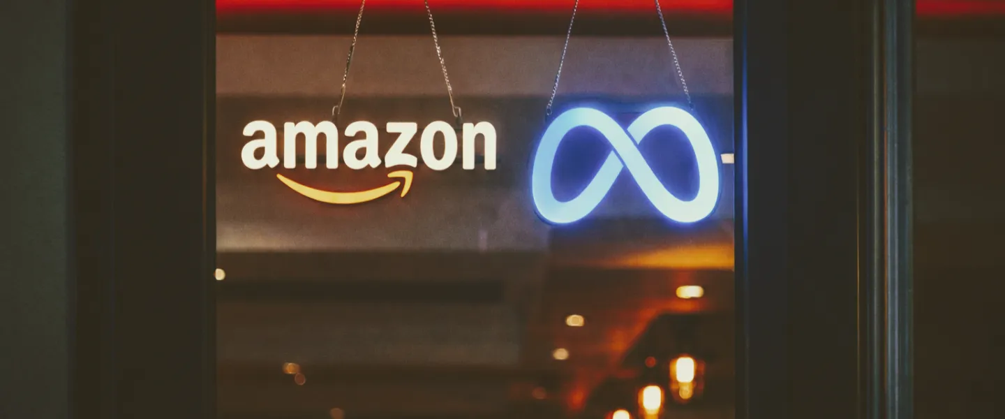 Puerta de una tienda que tiene carteles de neon con los logos de Amazon y Meta