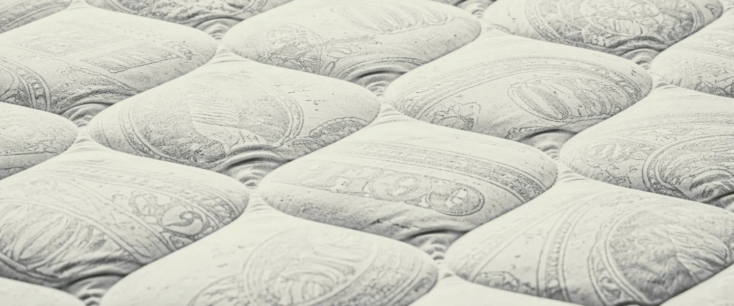 Primer plano de un colchón blanco con detalles en bajorrelieve de elementos de dólares