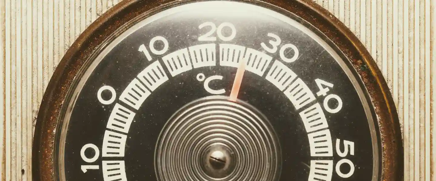 Primer plano de un termómetro circular con su aguja marcando los 25 grados centigrados