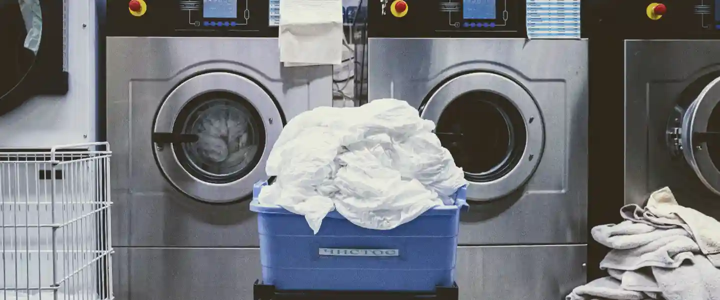 Cesto de ropa frente a unos lavarropas