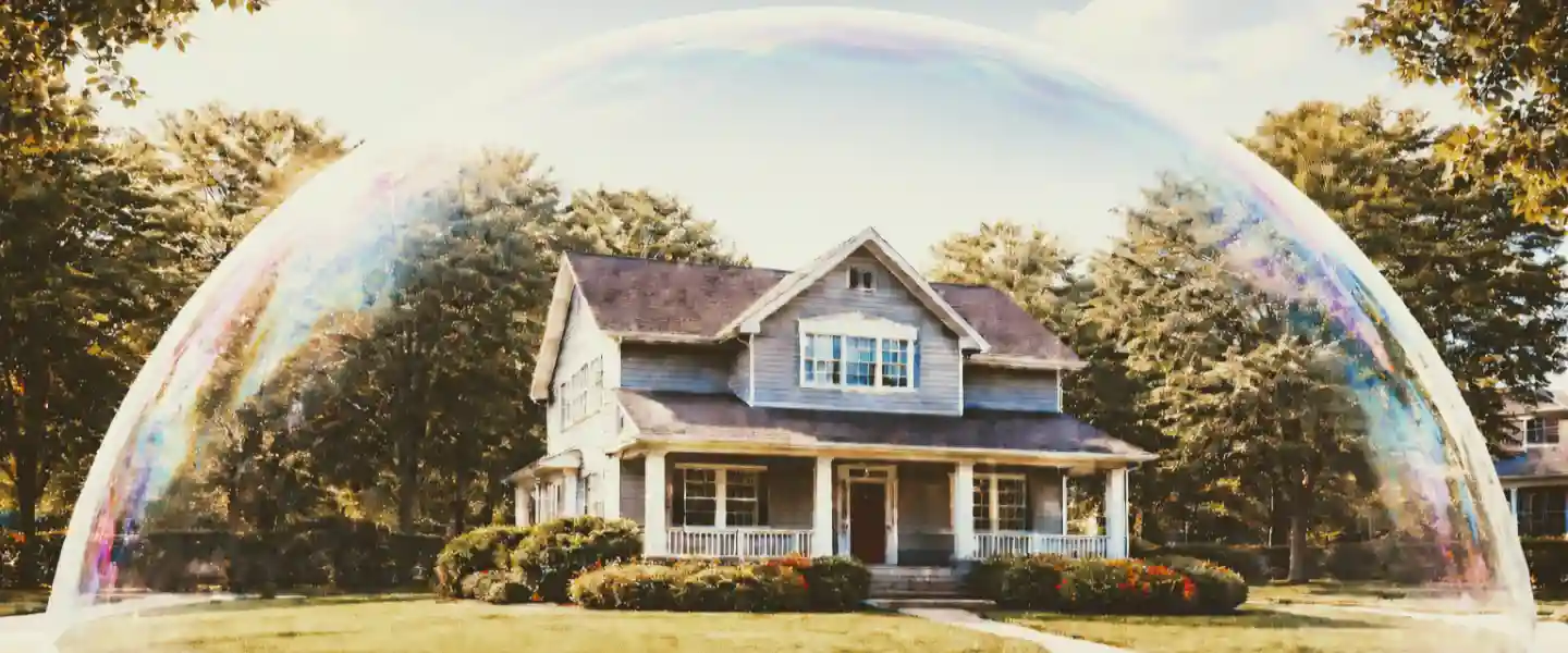Casa de dos pisos de madera encerrada en una pompa de jabón apoyada sobre el pasto
