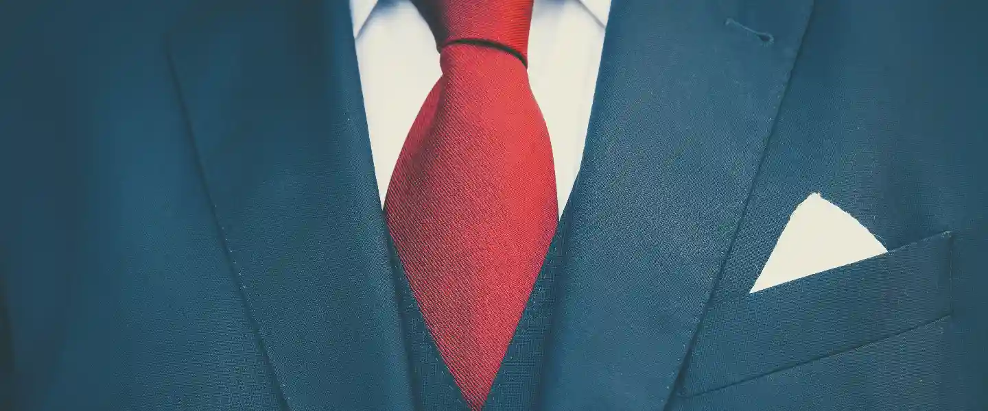 Primerisimo primer plano de un traje azul con camisa blanca y corbata roja y pañuelo blanco